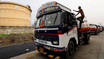 A man climbs an an oil tanker parked outside a fuel depot in Mumbai. Source: Reuters | File.
