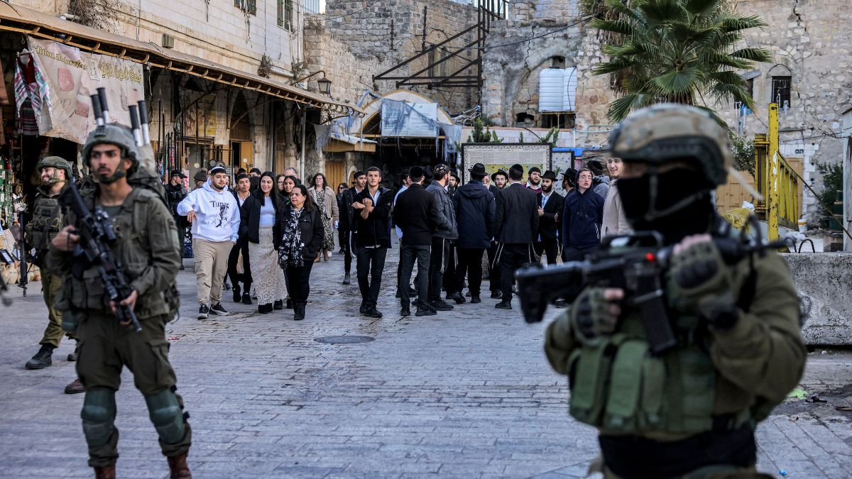 Israeli army soldiers stand guard as Israeli Jewish settlers tour the old market in the city of Hebron in the occupied West Bank on December 28, 2024. Image- AFP Israeli army soldiers stand guard as Israeli Jewish settlers tour the old market in the city of Hebron in the occupied West Bank on December 28, 2024. Image- AFP