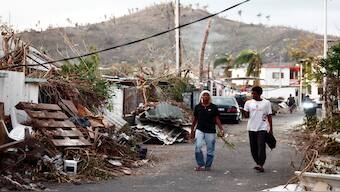 People walk on a street next to debris, in the aftermath of Cyclone Chido, in Pamandzi, Mayotte, France, on Tuesday. Reuters