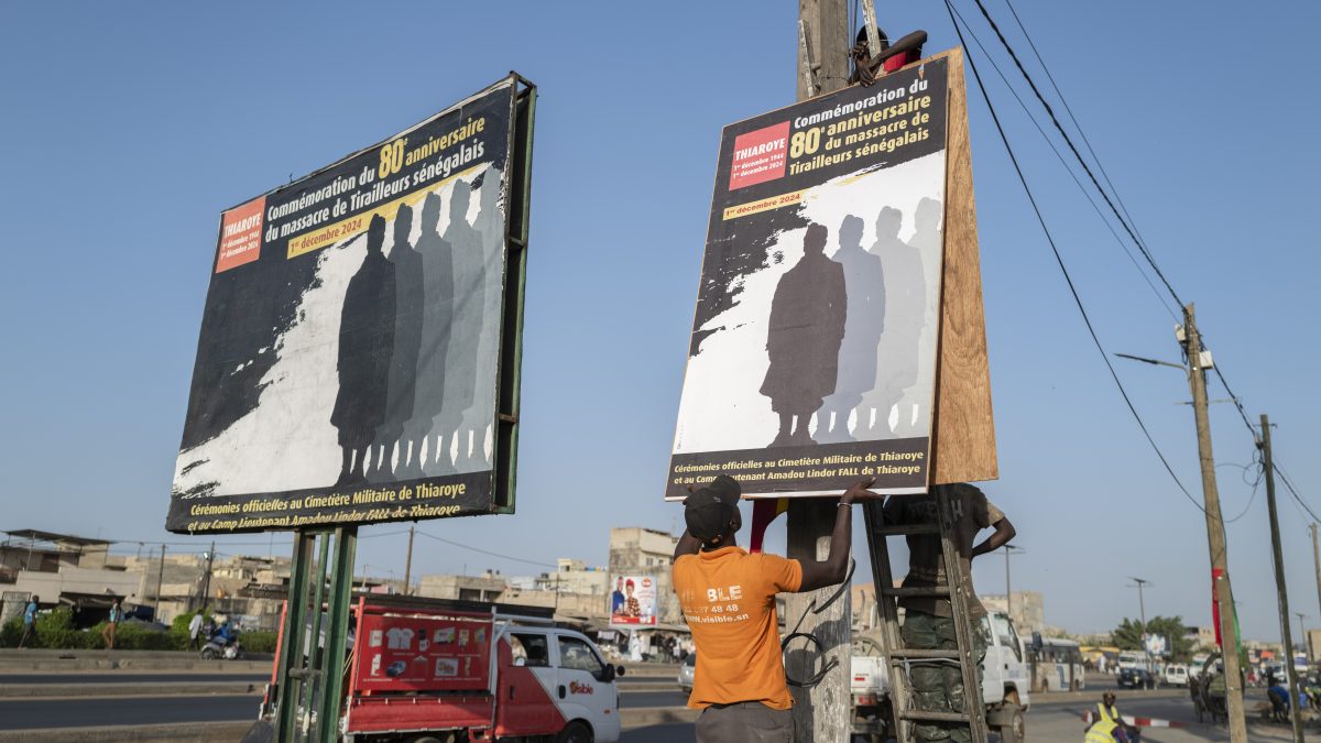 Workers put up a poster marking the 80th anniversary of the Thiaroye massacre Thiaroye, Senegal. AP Workers put up a poster marking the 80th anniversary of the Thiaroye massacre Thiaroye, Senegal. AP