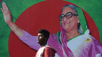 A Bangladeshi man walks past a photo of Prime Minister Sheikh Hasina, in Dhaka. Source: AFP.