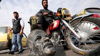An opposition fighter riding a motorcycle steps on a broken bust of the late Syrian President Hafez Assad, in Damascus, Syria, on December 8, 2024. AP