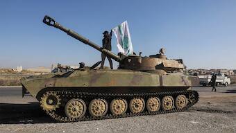 A rebel fighter stands atop of a military vehicle as he carries a Hayat Tahrir al-Sham flag in Saraqeb town in northwestern Idlib province, Syria December 1, 2024. Reuters