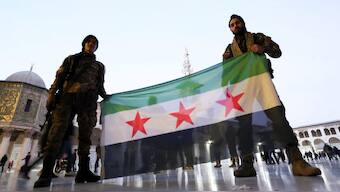 Rebel fighters pose as they hold a Syrian opposition flag inside the Umayyad Mosque, after rebels seized the capital and ousted Bashar al-Assad, in Damascus, Syria December 9, 2024. Source: Reuters. 