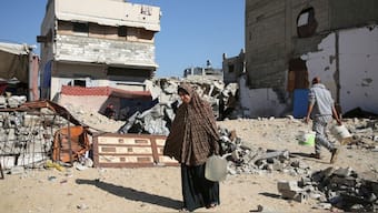 A displaced Palestinian woman, Makram Hamdouna, carries a water container outside her shelter, in Khan Younis in the southern Gaza Strip December 19, 2024. Reuters