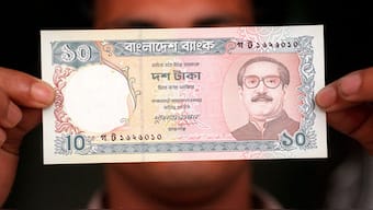 A local bank staff holds the a10 Taka currency issued by the central bank with the bust of Bangladesh's founder Sheikh Mujibur Rahman, who was assassinated in a 1975 military coup. Now, the interim government has ordered for new currency notes. File image/AFP