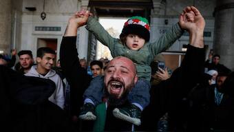A man carrying a child reacts, as people attend the first Friday prayers inside the Umayyad Mosque, after fighters of the ruling Syrian body ousted Bashar al-Assad, in the Damascus old city, Syria, on December 13. The country stares at uncertainty with rebels at the helm. Reuters