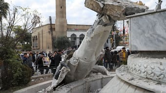 People stand near a damaged statue of former Syrian president Hafez al-Assad after Syrian rebels announced that they have ousted President Bashar al-Assad, in Qamishli, Syria on Sunday (December 8). Reuters