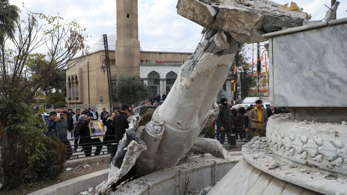 People stand near a damaged statue of former Syrian president Hafez al-Assad after Syrian rebels announced that they have ousted President Bashar al-Assad, in Qamishli, Syria on Sunday (December 8). Reuters People stand near a damaged statue of former Syrian president Hafez al-Assad after Syrian rebels announced that they have ousted President Bashar al-Assad, in Qamishli, Syria on Sunday (December 8). Reuters