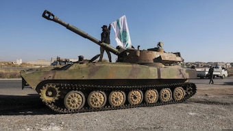 A rebel fighter stands atop of a military vehicle as he carries a Hayat Tahrir al-Sham flag in Saraqeb town in northwestern Idlib province, Syria. Reuters