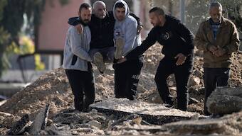 Palestinians displaced by an Israeli military operation evacuate from the Jenin refugee camp in the West Bank carrying an elderly man over rubble, on Thursday. AP