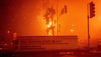 The Palisades Fire burns behind a sign for Will Rogers State Beach in the Pacific Palisades neighbourhood of Los Angeles on January 7, 2025. AP