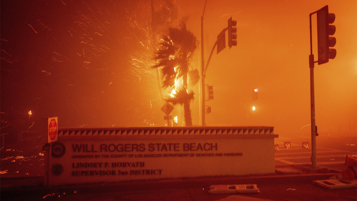 The Palisades Fire burns behind a sign for Will Rogers State Beach in the Pacific Palisades neighbourhood of Los Angeles on January 7, 2025. AP The Palisades Fire burns behind a sign for Will Rogers State Beach in the Pacific Palisades neighbourhood of Los Angeles on January 7, 2025. AP