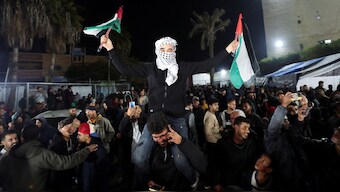 A man waves Palestinian flags as Palestinians react to news on a ceasefire deal with Israel, in Deir Al-Balah in the central Gaza Strip, January 15, 2025. File Image/Reuters