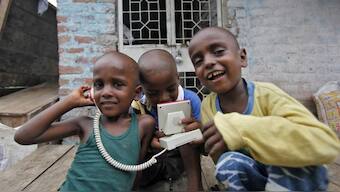 Boys play with a toy telephone as they react to the camera at a slum in New Delhi. Source: Reuters | File.