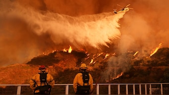 Firefighters watch as water is dropped on the Palisades Fire in Mandeville Canyon Saturday, Jan. 11, 2025, in Los Angeles. Image- AP