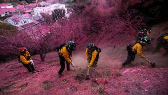 Firefighters work to clear a firebreak as the Palisades Fire burns in Mandeville Canyon, California, US. Reuters
