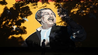 A man is silhouetted as he passes by a graffiti of Bangabandhu Sheikh Mujibur Rahman, in Dhaka, Bangladesh. Reuters