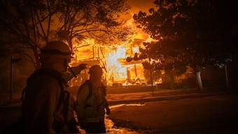 A firefighter walks by a home on flames from the Palisades Fire in the Pacific Palisades neighbourhood of Los Angeles, California. The fast-moving wildfire is threatening homes in the coastal neighbourhood amid intense Santa Ana Winds and dry conditions in Southern California. AFP