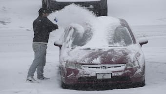 A person dusts snow off of a car during a winter storm, in Cincinnati. AP