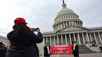 A woman clicks a picture as people hold a placard in favour of US President-elect Donald Trump in front of the US Capitol building ahead of the presidential inauguration in Washington, on, January 18. The oath ceremony has now been moved indoors because of the freezing temperatures in the capital city. Reuters
