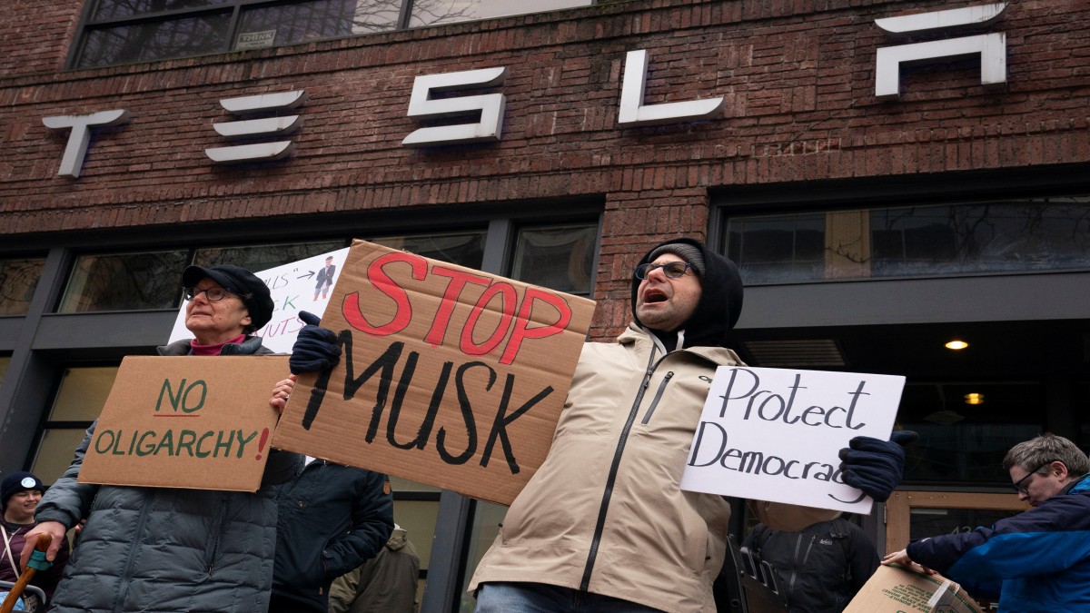 A demonstrator holds a sign during a protest at electric carmaker Tesla's showroom in Seattle, Washington, US. Reuters A demonstrator holds a sign during a protest at electric carmaker Tesla's showroom in Seattle, Washington, US. Reuters