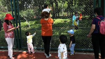 Children play next to adults at a park in Beijing, China. File image/ Reuters
