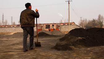 (File) A villager looks towards a rare earth smelting plant as he takes a break from shovelling cast-off tailings of crushed mineral ore that contain rare earth metals in Xinguang Village, located on the outskirts of the city of Baotou in China's Inner Mongolia Autonomous Region. Reuters