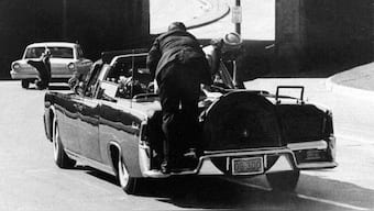 US President John F Kennedy slumps down in the back seat of the presidential limousine as it speeds along Elm Street toward the Stemmons Freeway overpass in Dallas, Texas, after being fatally shot, November 22, 1963. US First lady Jacqueline Kennedy leans over the president as Secret Service Agent Clint Hill pushes her back to her seat. File Image/AP