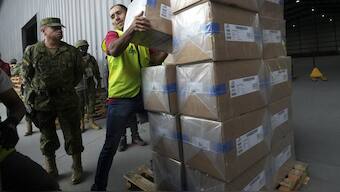 A National Electoral Council employee helps to load electoral kits at a distribution center, in preparation for the general election, in Quito, Ecuador. AP
