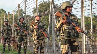 BSF personnel stand guard near a fence. PTI