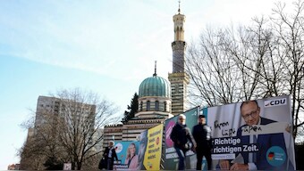 People walk past an election campaign poster of Friedrich Merz, Christian Democratic Union (CDU) party candidate for chancellor, the day before the parliamentary election, in Potsdam, Germany. Reuters