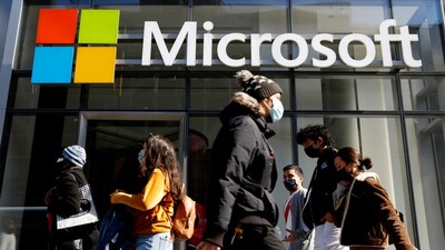 People walk past a building with the Microsoft logo. (Representative Image, Credit: Reuters)