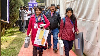 In this image provided by PIB, officials carry Electronic Voting Machines (EVMs) and other necessary inputs required for the Delhi Assembly Election 2025 at a distribution centre, at Atal Adarsh Bengali Balika Vidyalaya, Gole Market, in New Delhi, Tuesday, February 4, 2025. PTI