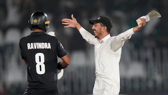 A spectator carrying a photograph of 'Tehreek-e-Labaik Pakistan'  leader Saad Rizvi hugs Rachin Ravindra after invading the playing area at the Rawalpindi Cricket Stadium during the Champions Trophy Group A match between Bangladesh and New Zealand. AP