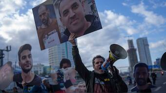 A demonstrator holding photos of freed Israeli hostage Eli Sharabi before and after his captivity blocks a highway during a protest demanding all hostages release from Hamas captivity, in Tel Aviv, Israel, Thursday, Feb. 13, 2025. Image- Reuters