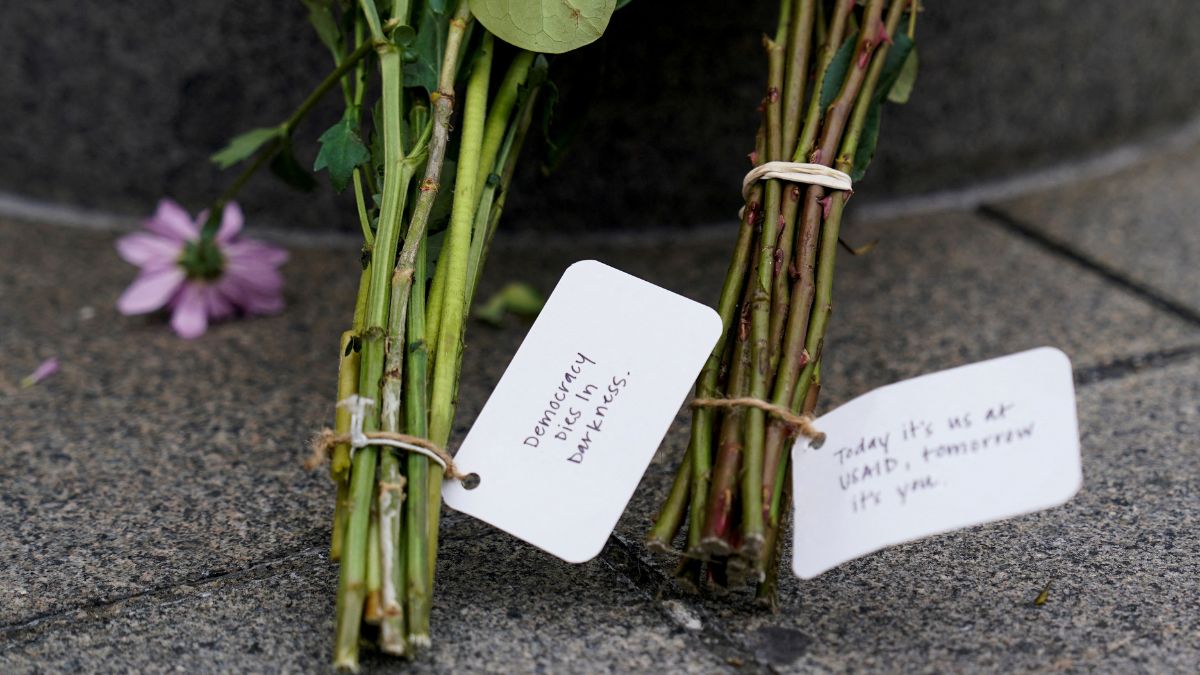 Flowers lie at the base of a flagpole, as the USAID building sits closed. Reuters
Flowers lie at the base of a flagpole, as the USAID building sits closed. Reuters