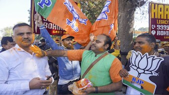 BJP workers celebrate as trends show the party's victory in Delhi Assembly polls, during counting of votes in New Delhi. PTI