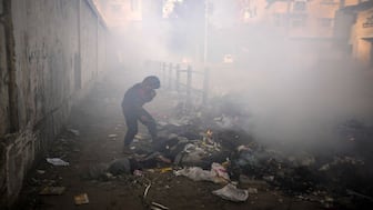 A boy covers his face as he plays by throwing paper onto a burning pile of garbage in the streets in Gaza City. Buildings have been flattened, thousands have died since Israel began its war in Gaza against Hamas following the October 7, 2023 attack. AP