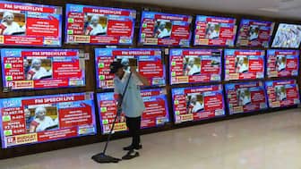 Finance Minister Nirmala Sitharaman is seen on television screens announcing the Budget as a man cleans in an electronic shop in Mumbai, India. AP
