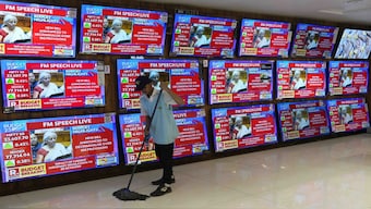 Finance Minister Nirmala Sitharaman is seen on television screens announcing the Budget as a man cleans in an electronic shop in Mumbai, India. AP