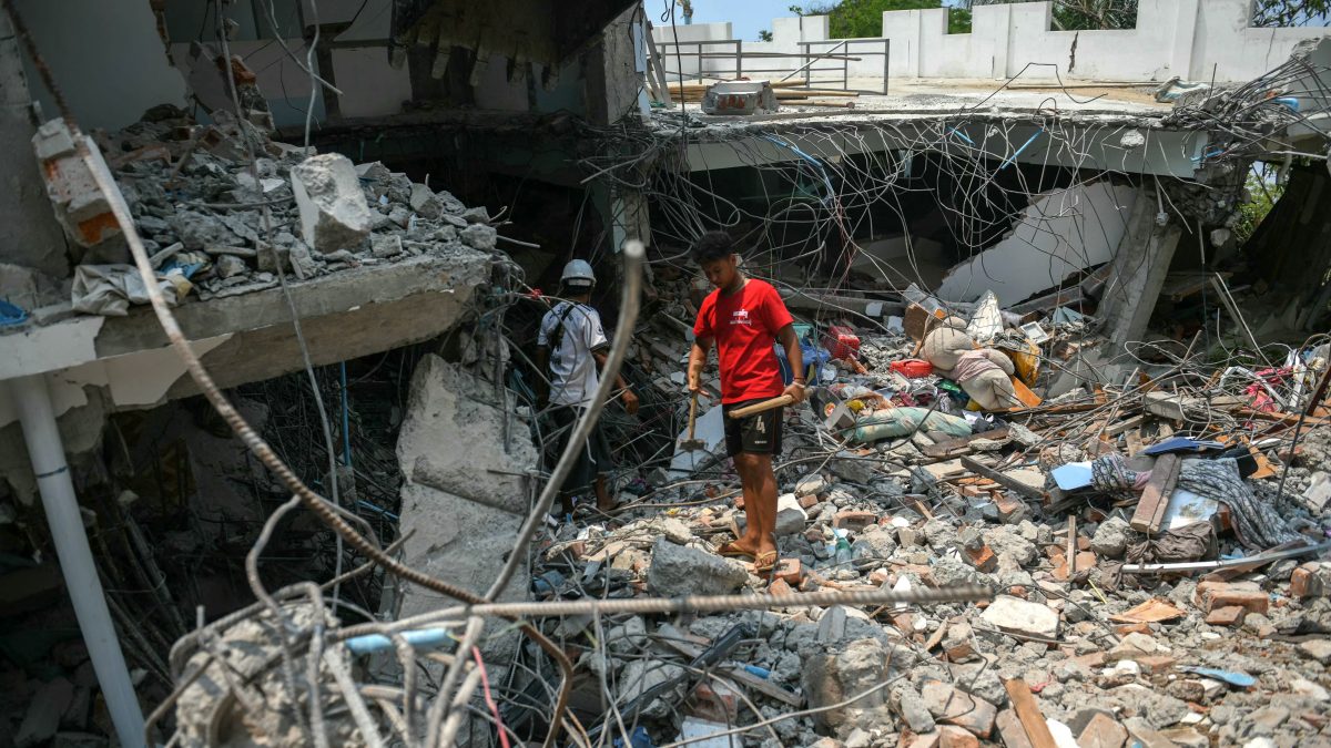 People stand next to a destroyed building as rescuers look through the rubble to find survivors in Mandalay on March 29, 2025, a day after an earthquake struck central Myanmar. AFP People stand next to a destroyed building as rescuers look through the rubble to find survivors in Mandalay on March 29, 2025, a day after an earthquake struck central Myanmar. AFP