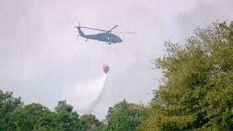 A helicopter drops water to help contain a fire in the Carolina Forest area west of the coastal resort city of Myrtle Beach, S.C. AP