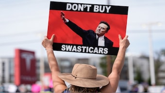 Jennifer Walker stands with other demonstrators during a protest of automaker billionaire CEO, Elon Musk near a Tesla vehicle dealership, Saturday, March 8, 2025, in Decatur, Ga. AP