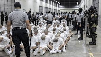 In this photo provided by El Salvador's presidential press office, a prison guard transfers deportees from the U.S., alleged to be Venezuelan gang members, to the Terrorism Confinement Center in Tecoluca, El Salvador. AP