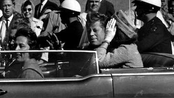 President John F. Kennedy waves from his car in a motorcade approximately one minute before he was shot, Nov. 22, 1963, in Dallas. File image/ AP