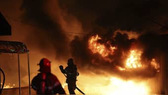 Firefighters extinguish a fire at a factory building that has been engulfed in a wildfire in Uiseong, South Korea. AP