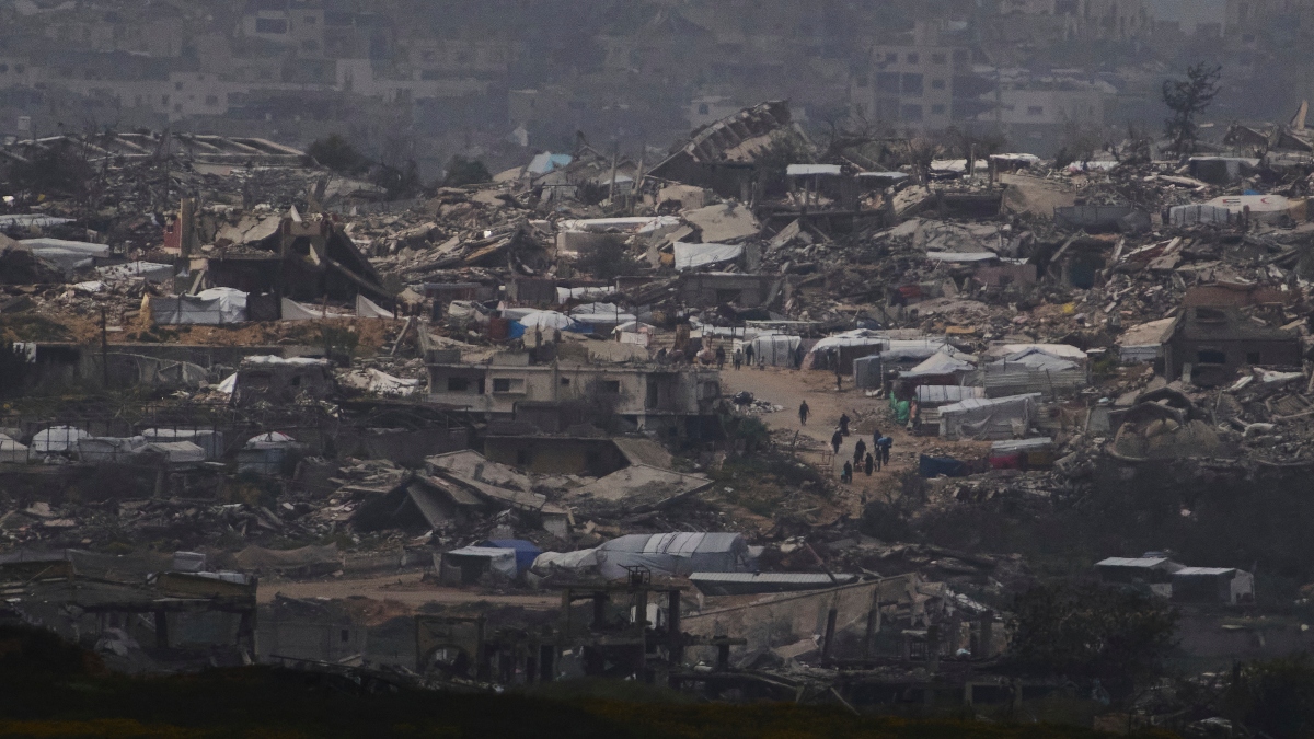 People walk surrounded by buildings destroyed during the Israeli air and ground offensive in the Gaza Strip as seen from southern Israel, on Thursday. AP People walk surrounded by buildings destroyed during the Israeli air and ground offensive in the Gaza Strip as seen from southern Israel, on Thursday. AP