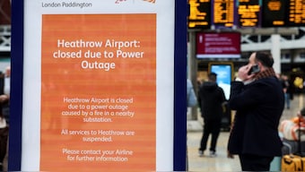 A man speaks to the phone near a notice about a power outage at Heathrow International Airport, after a fire at a electrical substation wiped out power at the airport, at the Paddington railway station in London, UK, March 21, 2025. File Image/Reuters
