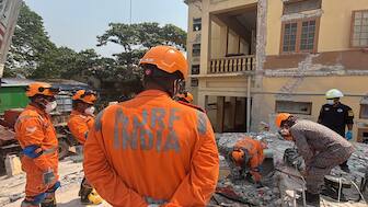 Indian and Myanmar rescuers try to carry a dead body at U Hla Thein Buddhist monastery that collapsed in Friday's earthquake in Mandalay, Myanmar, on Monday. AP